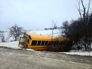 School bus partially submerged in snow and water.