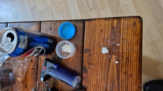 Red and blue soda can, clear plastic lid, white powder in a small container, wooden table