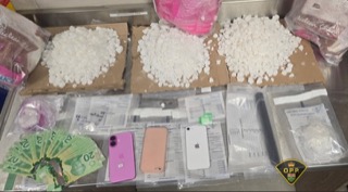 Stacks of Canadian twenty-dollar bills, two smartphones, and packages of a white powdery substance.