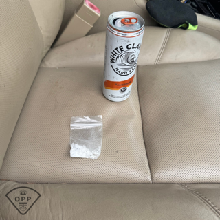 White Claw tangerine can next to a small bag of white powder