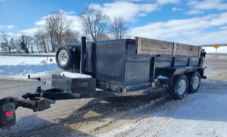 Black dump trailer with snow on top and tires.
