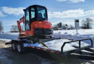 Mini excavator on a trailer, snow-covered ground