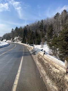 Winding road covered in snow, evergreen trees and snow-covered hillside