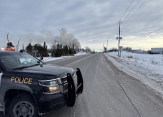 Police cruiser, snowy road, smoke in distance