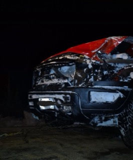 Black pickup truck covered in foam and grime.