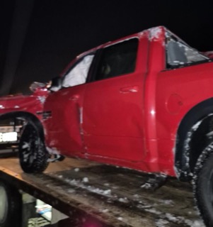 Damaged red pickup truck on a trailer