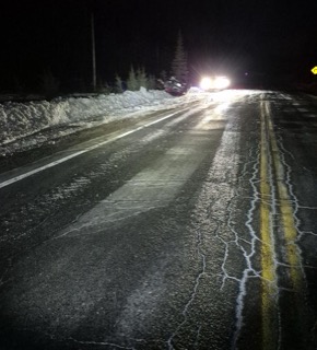 Snow-covered road with headlights approaching.