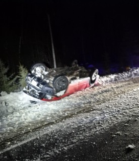 Red car overturned on a snowy road.