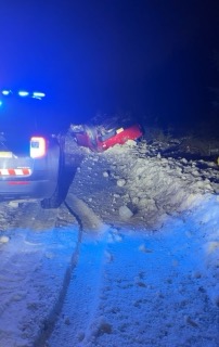 Vehicle partially submerged in snow and debris.