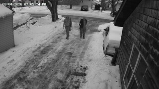 Two figures walking on snow-covered street