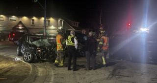 Damaged black car, emergency responders, nighttime
