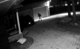 Person walking near a car and building.