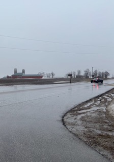 Wet road and grassy field.