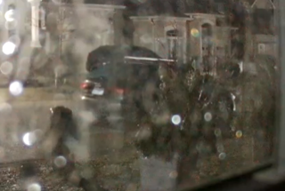 Blurred image of a dark car driving on a wet street.