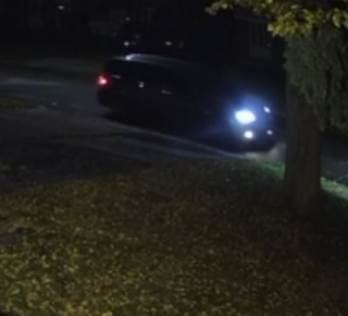 Car headlights illuminate a dark road.