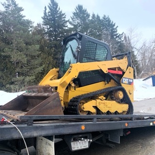 Yellow skid steer on a flatbed trailer.