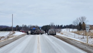Police vehicles and people on a snowy road.