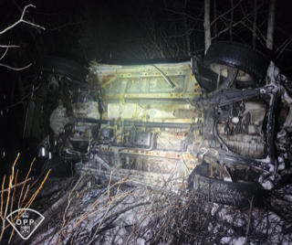 Damaged vehicle in a wooded area.