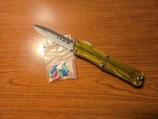 Folding knife with yellow handle, small bag of pills