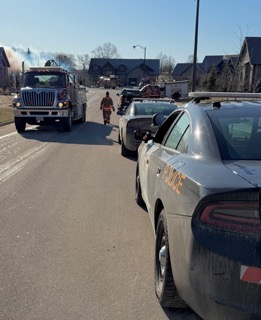 Police car, fire truck, and bystanders on a residential street