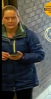 Man in a blue jacket holding a card.