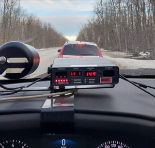 Dashboard with radar display showing 149km/h, snow-covered field and sky visible through windshield