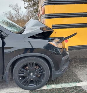 Damaged black SUV front end, yellow school bus side.