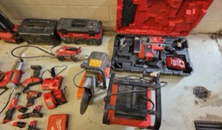 Red and black power tools and toolboxes on a concrete floor.