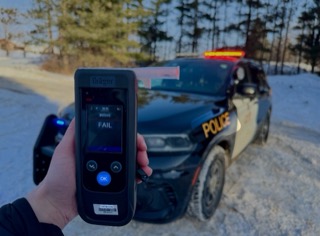 Police officer holding a breathalyzer; screen reads &quot;FAIL&quot; and &quot;00045&quot;