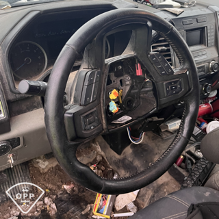 Black leather steering wheel with controls, dashboard visible