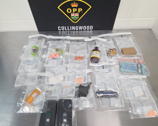 Small baggies of pills and powder, digital scale, clear bottles, and a smartphone on a black surface.