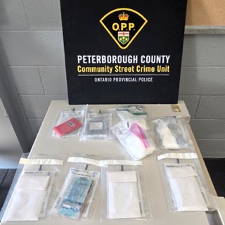 Canadian currency in baggies, alongside small baggies of a white powdery substance, and a red package.