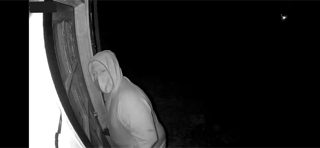Person in a hooded robe near a window