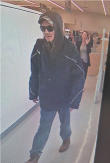 Person in a black hooded jacket and jeans, sunglasses