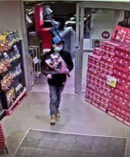 Person wearing a mask and jacket, walking with a gift box
