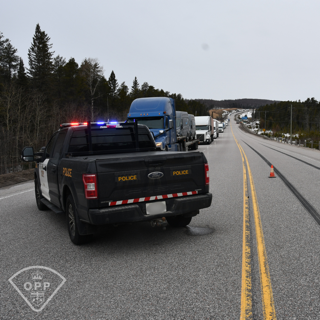 Police truck with flashing lights, line of vehicles ahead on a highway