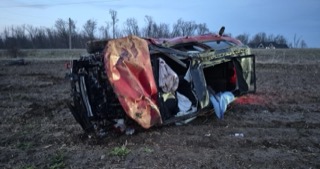 Wrecked red pickup truck in a field.