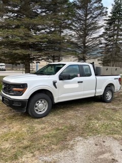 White pickup truck parked on gravel.