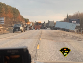 Semi-truck and trailer partially blocking a highway.