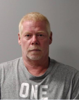 Man with a shaved head and short beard, wearing a gray t-shirt that reads &quot;ONE&quot;