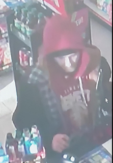 Person wearing a red beanie and black jacket, holding a vape pen.