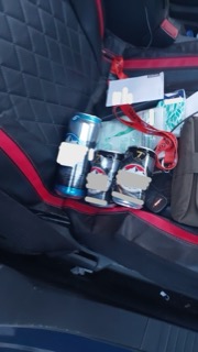 Four cans of beer in a car door pocket.