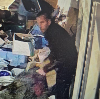 Man in black shirt standing amid cardboard boxes