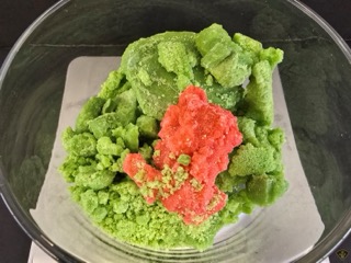 Green and red textured powder in a clear container.