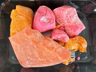 Pink and orange cake pieces in a clear container.