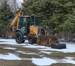 Case backhoe with bucket and forks, snow-covered ground