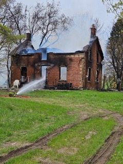 Damaged brick house with smoke rising.