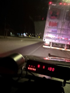 Fire truck with flashing red and white lights, speed reading 100