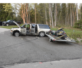 Damaged SUV and trailer with snowmobile