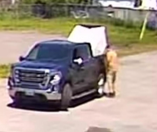 Dark pickup truck with open bed, person standing nearby